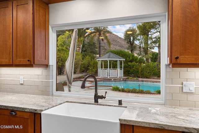 kitchen with light stone countertops, sink, and decorative backsplash