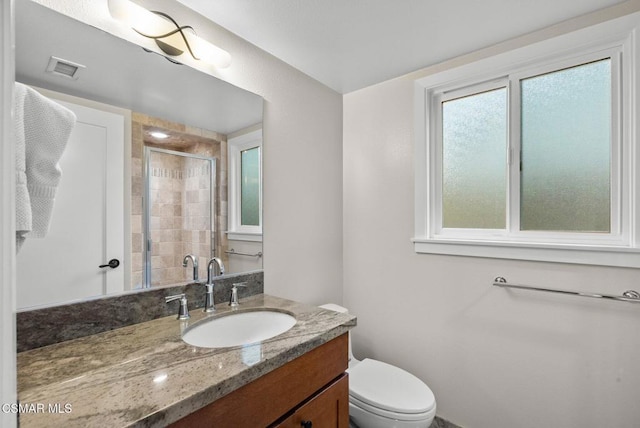 bathroom with toilet, a shower with door, and vanity