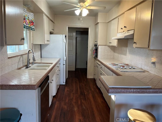 kitchen with white cabinetry, kitchen peninsula, white appliances, dark hardwood / wood-style flooring, and sink