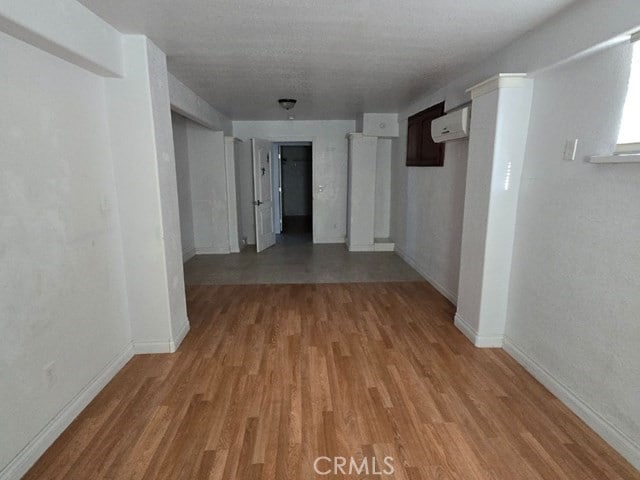 hall with light wood-type flooring and a wall mounted AC