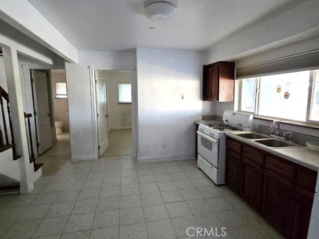 kitchen with dark brown cabinetry, white gas range oven, and sink