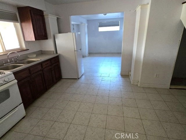 kitchen featuring sink, white appliances, dark brown cabinetry, and plenty of natural light