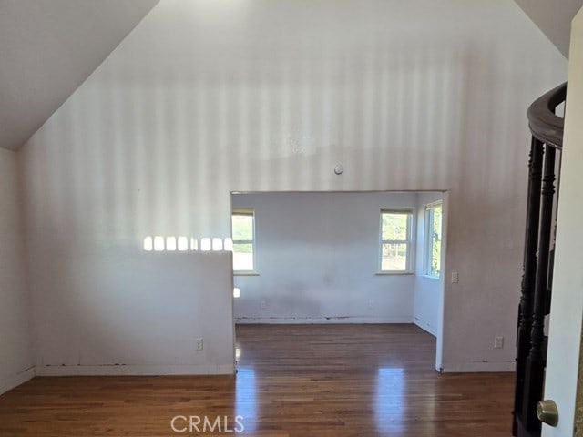 unfurnished living room with vaulted ceiling, dark hardwood / wood-style floors, and a wealth of natural light