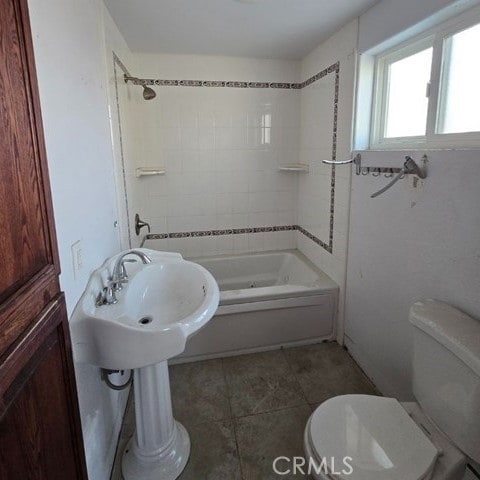 bathroom with toilet and tiled shower / bath