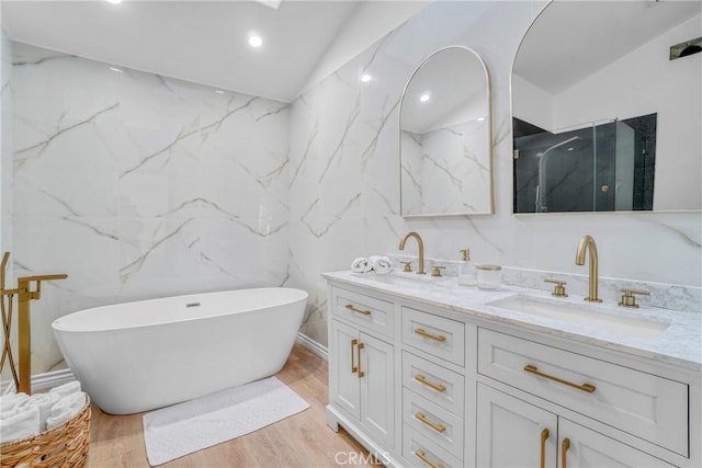 bathroom with vaulted ceiling, a bathtub, hardwood / wood-style floors, and vanity