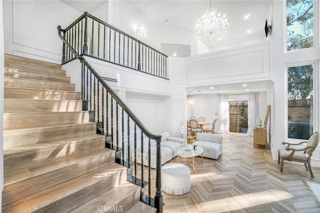 stairway with a high ceiling, parquet floors, and a notable chandelier