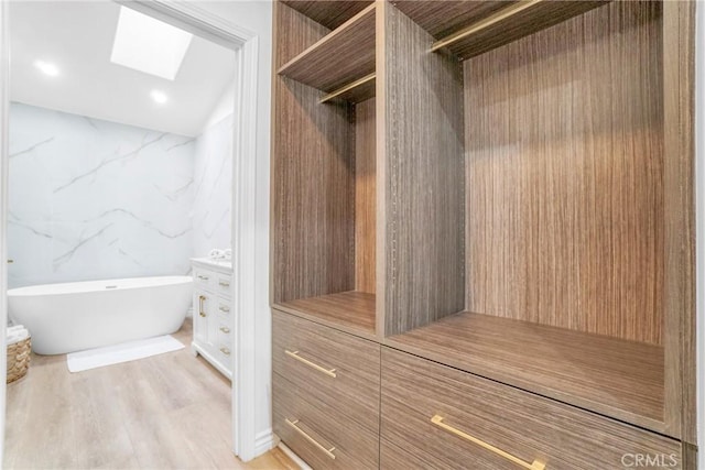 spacious closet featuring light wood-type flooring and a skylight