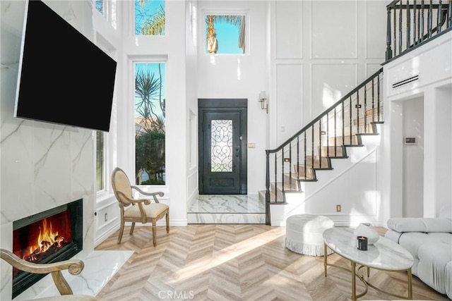 foyer entrance with a towering ceiling, light parquet flooring, and a premium fireplace