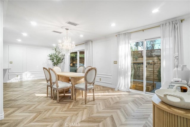 dining space with light parquet floors and a notable chandelier