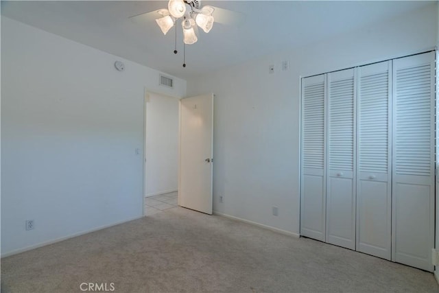 unfurnished bedroom with light colored carpet, ceiling fan, and a closet