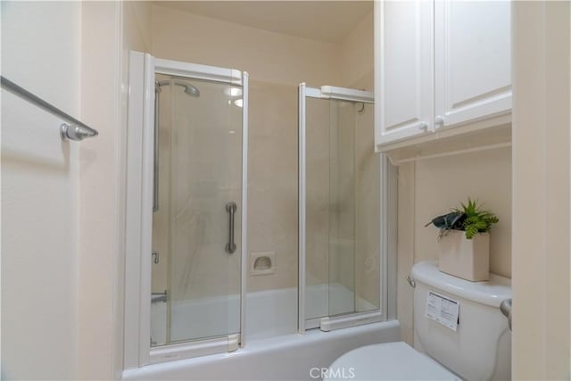 bathroom with combined bath / shower with glass door and toilet