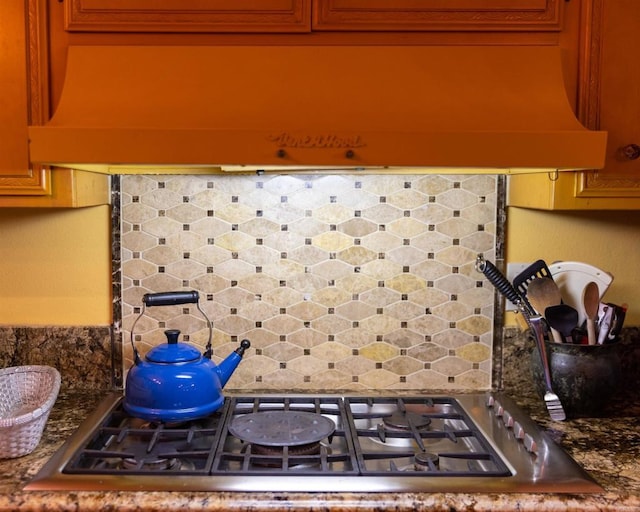 details featuring premium range hood, backsplash, and stainless steel gas stovetop