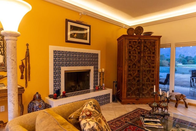 living room with light tile patterned floors, ornamental molding, and a tiled fireplace