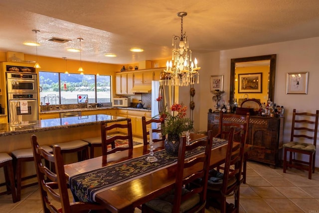 tiled dining area featuring a textured ceiling, an inviting chandelier, and sink