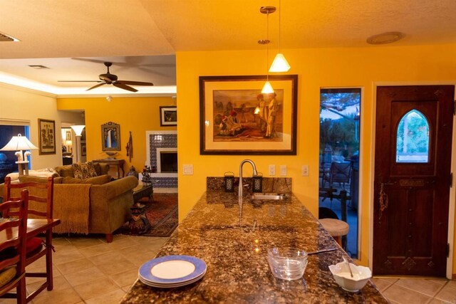 kitchen with decorative light fixtures, a fireplace, sink, ceiling fan, and light tile patterned floors