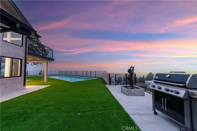 yard at dusk featuring a balcony, a patio area, and a fenced in pool