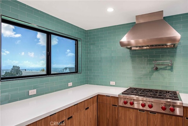 kitchen with exhaust hood, stainless steel gas cooktop, and decorative backsplash