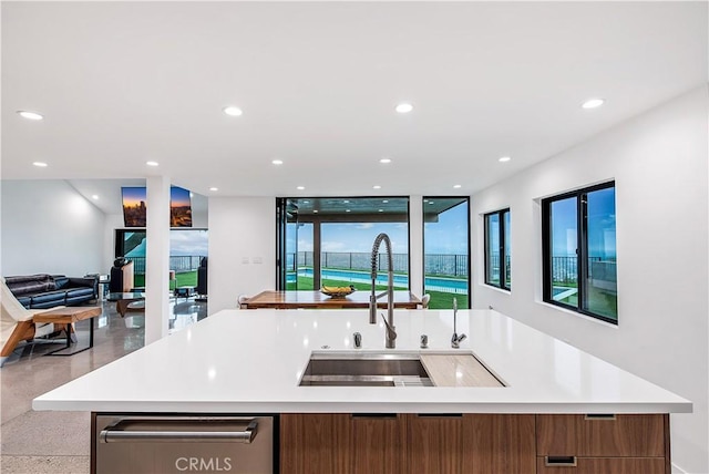 kitchen with floor to ceiling windows, a center island with sink, and sink