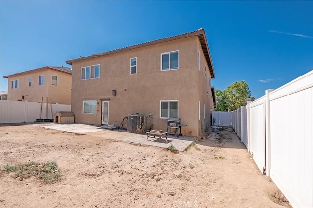 rear view of property with cooling unit, a fire pit, and a patio