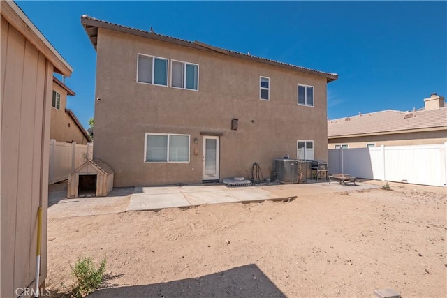 rear view of property with a patio area, central air condition unit, and an outdoor fire pit