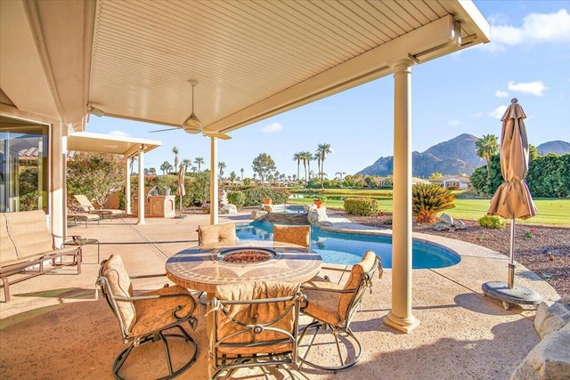 view of patio / terrace with ceiling fan, a mountain view, and a fire pit