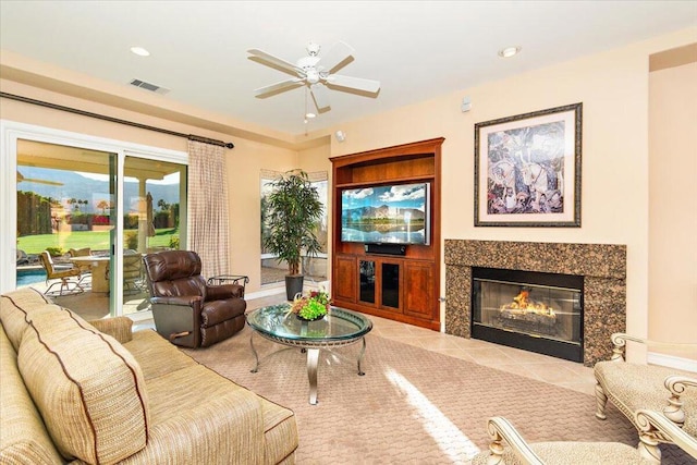 living room with ceiling fan and a high end fireplace