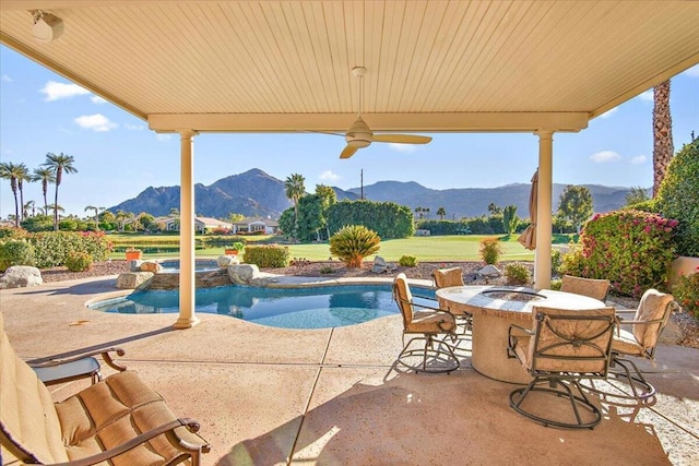 view of swimming pool with ceiling fan, a patio area, and a mountain view