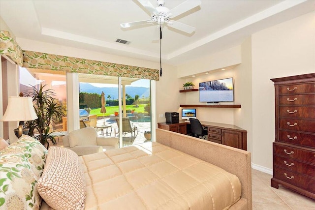 bedroom with ceiling fan, light tile patterned floors, access to exterior, and a tray ceiling