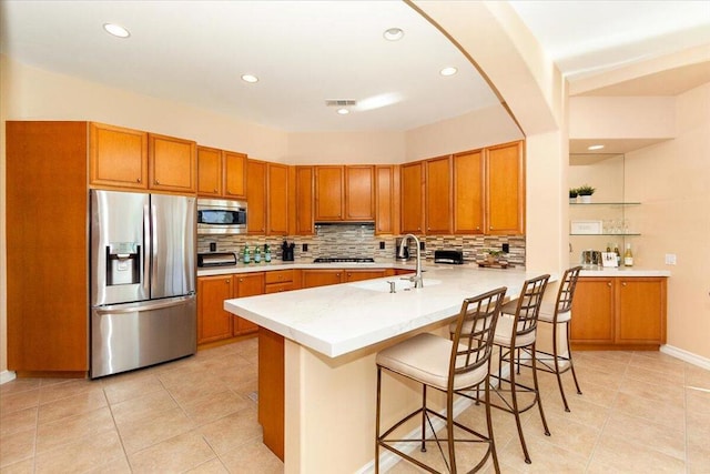 kitchen featuring appliances with stainless steel finishes, a kitchen bar, sink, kitchen peninsula, and light tile patterned floors