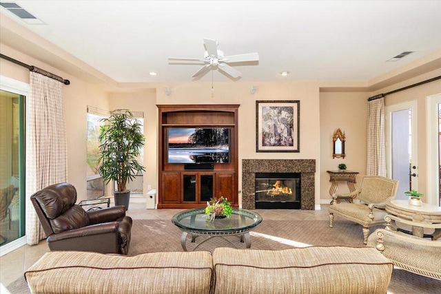 living room featuring a premium fireplace, light tile patterned floors, and ceiling fan