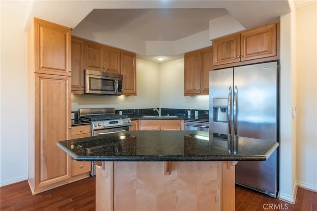 kitchen with a breakfast bar, appliances with stainless steel finishes, dark stone counters, and a center island