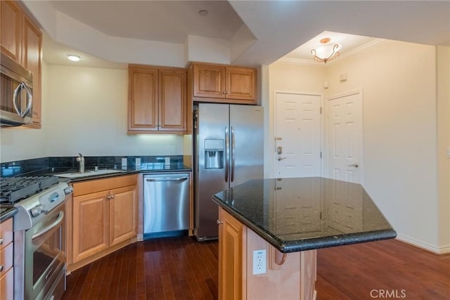 kitchen featuring appliances with stainless steel finishes, dark wood-style flooring, a sink, and dark stone countertops