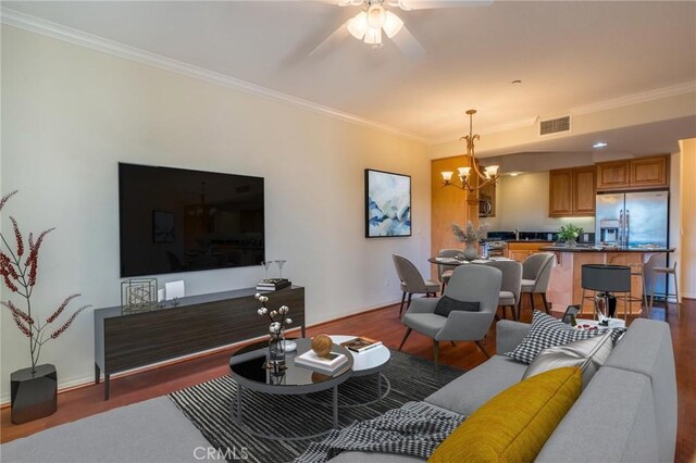 living area with wood finished floors, visible vents, and crown molding