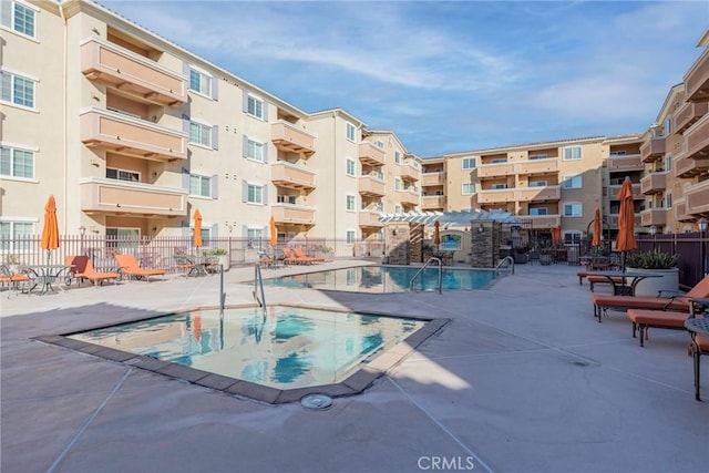 view of pool featuring a jacuzzi, fence, and a patio