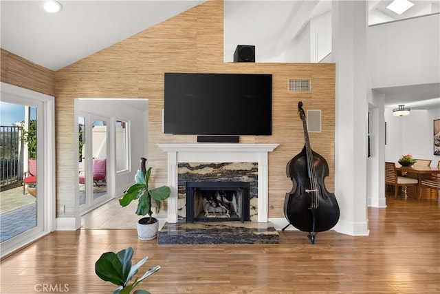 living room with hardwood / wood-style flooring, a premium fireplace, and high vaulted ceiling