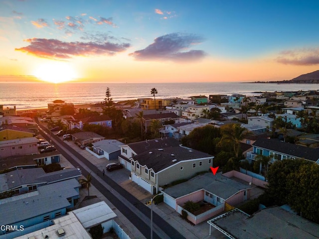 aerial view at dusk featuring a water view