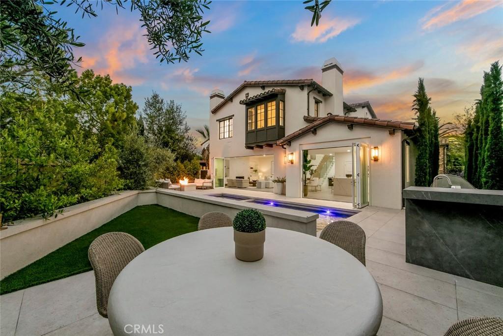 back house at dusk with an outdoor kitchen and a patio