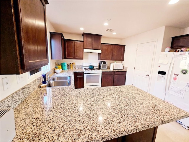 kitchen featuring kitchen peninsula, sink, white appliances, dark brown cabinetry, and light stone countertops