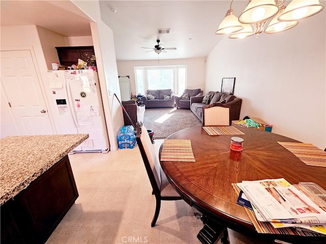 dining space featuring ceiling fan with notable chandelier and light colored carpet