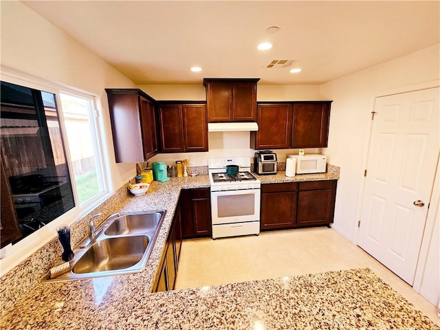 kitchen featuring sink, light stone counters, and white appliances