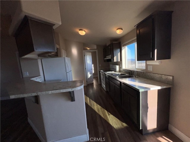 kitchen with a kitchen bar, dark wood-type flooring, sink, and white appliances