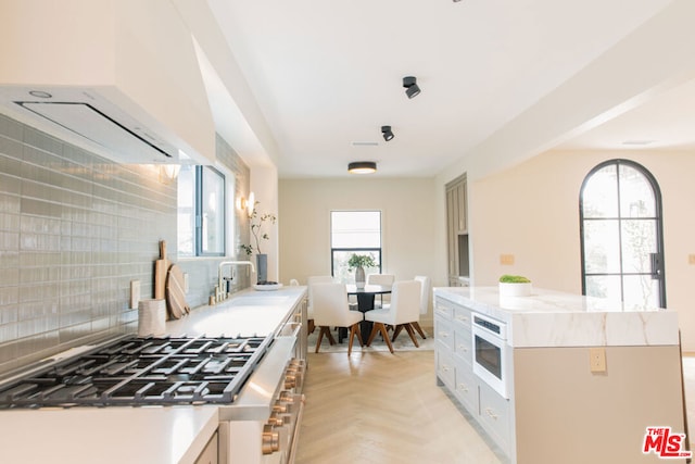 kitchen featuring ventilation hood, white microwave, light parquet flooring, stovetop, and sink