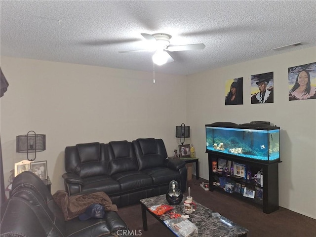 living room featuring ceiling fan, dark carpet, and a textured ceiling