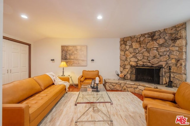 living room with lofted ceiling and a stone fireplace