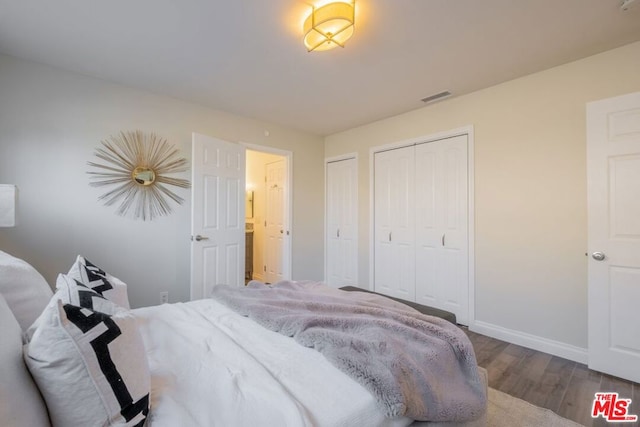 bedroom featuring multiple closets and hardwood / wood-style floors