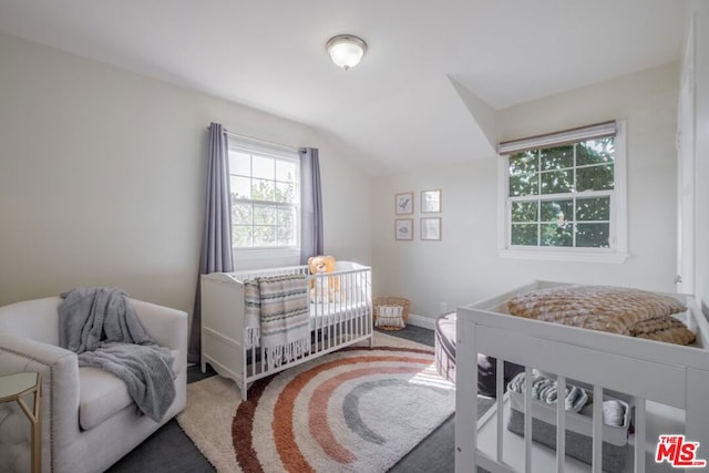 carpeted bedroom featuring a crib and vaulted ceiling