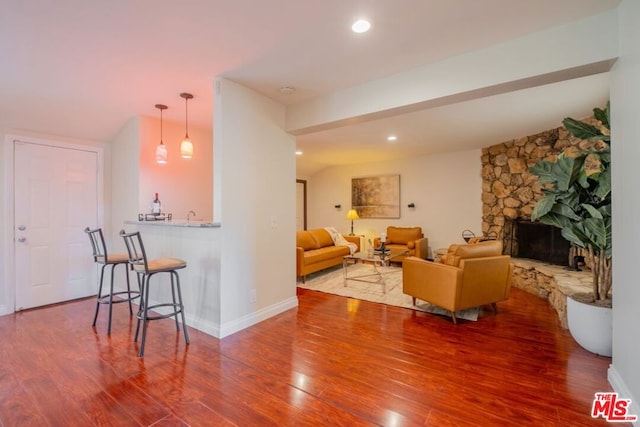 living room featuring a fireplace, wood-type flooring, and bar area