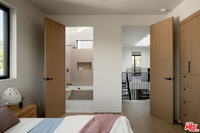 bedroom featuring ensuite bath and light hardwood / wood-style flooring