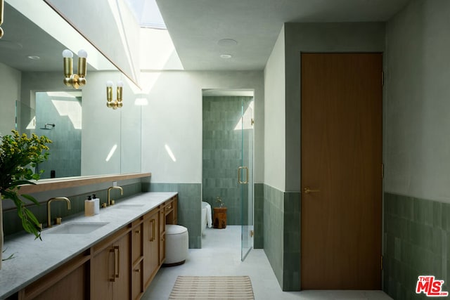 bathroom featuring a skylight, tile patterned flooring, tile walls, walk in shower, and vanity