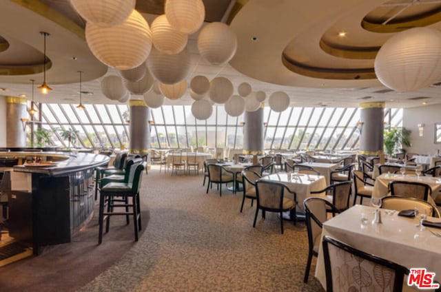 carpeted dining area with a raised ceiling